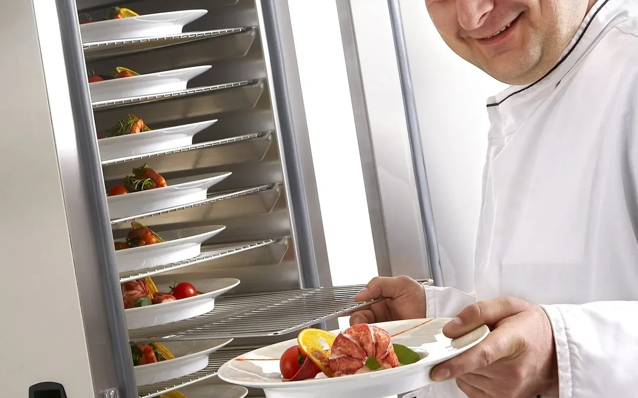 Chef servant une assiette maintenue à température dans une armoire de maintien Tournus Équipement